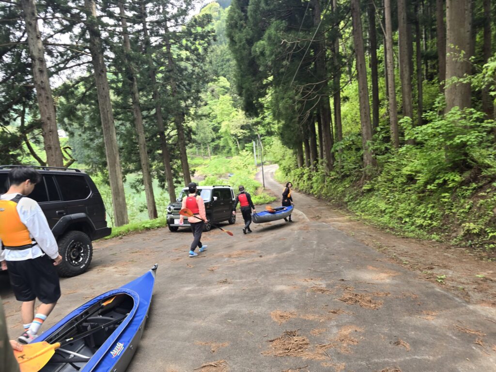 カヤックを持って只見川の川岸へ向かう参加者たち
