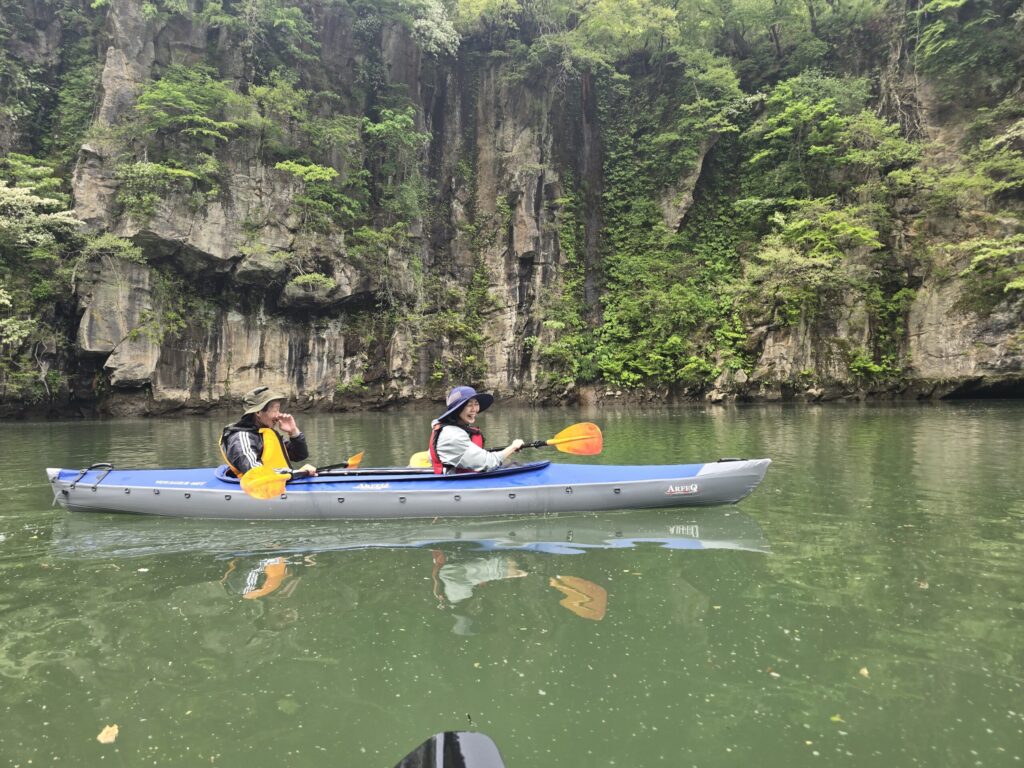 切り立った岩壁の前でカヤックを漕ぐご夫婦2組