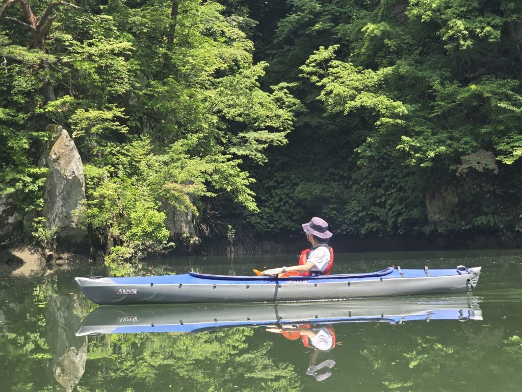 岩壁と新緑に囲まれた只見川を進むカヤック