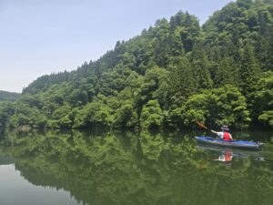 切り立つ岩壁と新緑の渓谷を進むカヤック