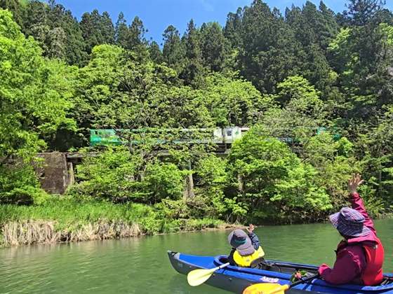 新緑の只見川で、川面から只見線の列車に手を振る親子