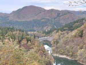 三島町の第一只見川橋梁を渡る只見線の列車。周囲の山が黄や赤に色づいている